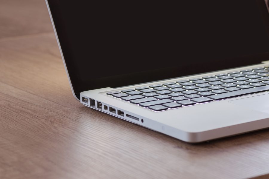 Close-up of a sleek silver laptop with a backlit keyboard on a wooden desk, perfect for tech themes.